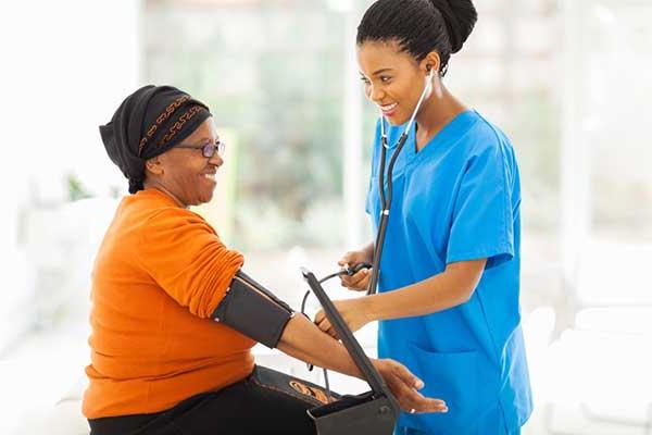 female medical worker checking womans blood pressure